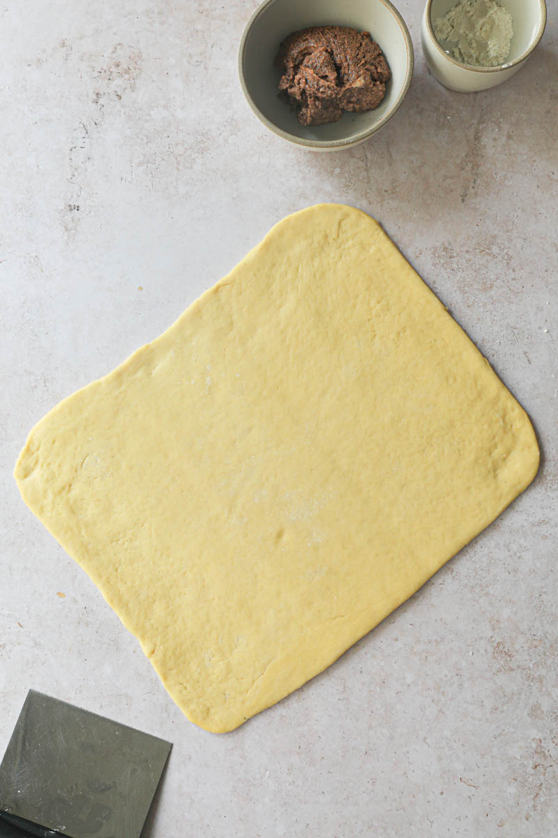 The rolled-out brioche dough with a scraper on the side.