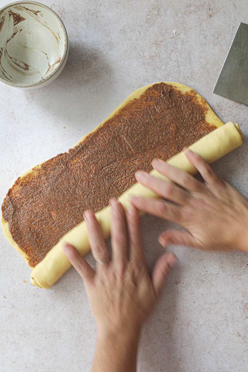 2 hands rolling the dough into a log.