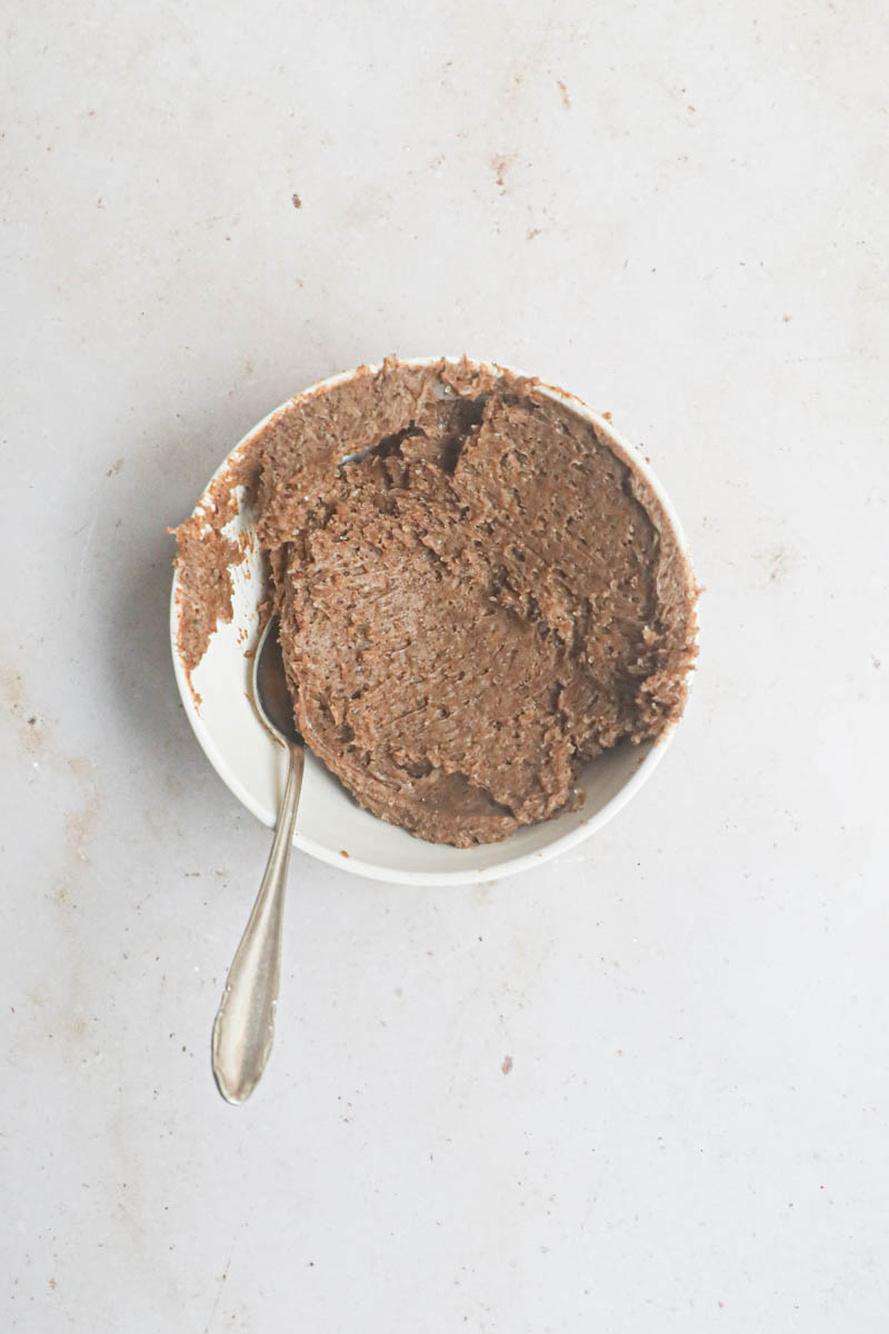 The cinnamon roll filling in a small bowl with a spoon on the side.