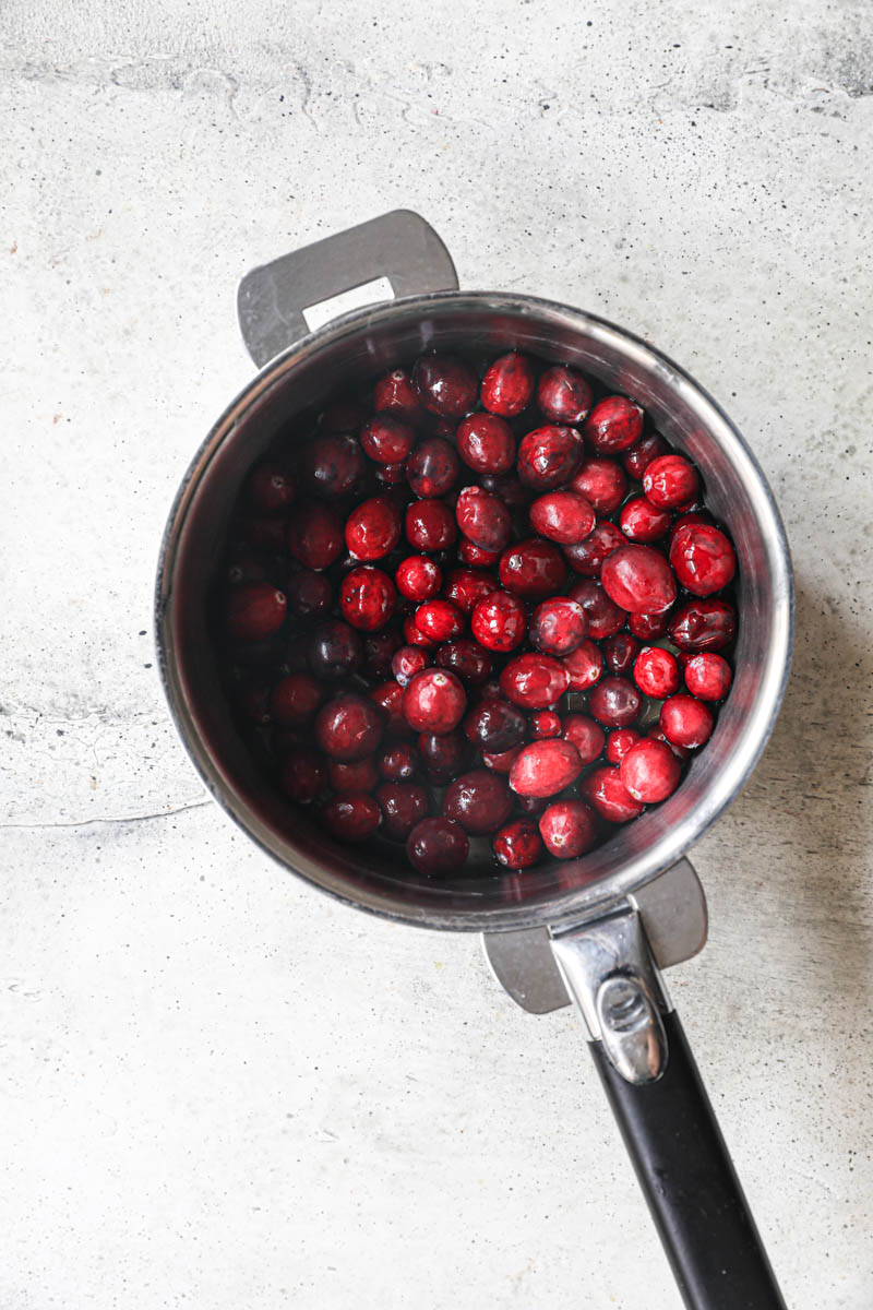 The cranberries and the orange juice inside a pan.