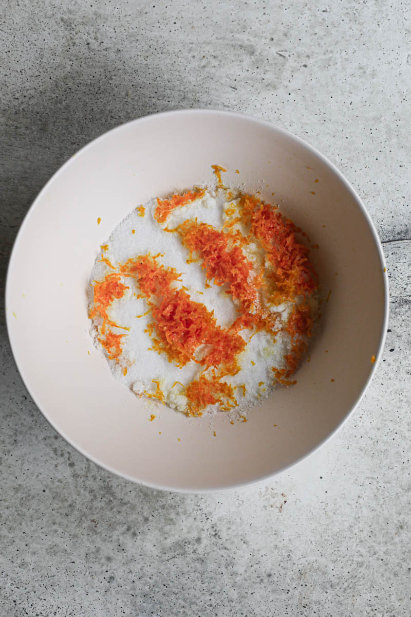 The sugar and orange zest inside a beige bowl.