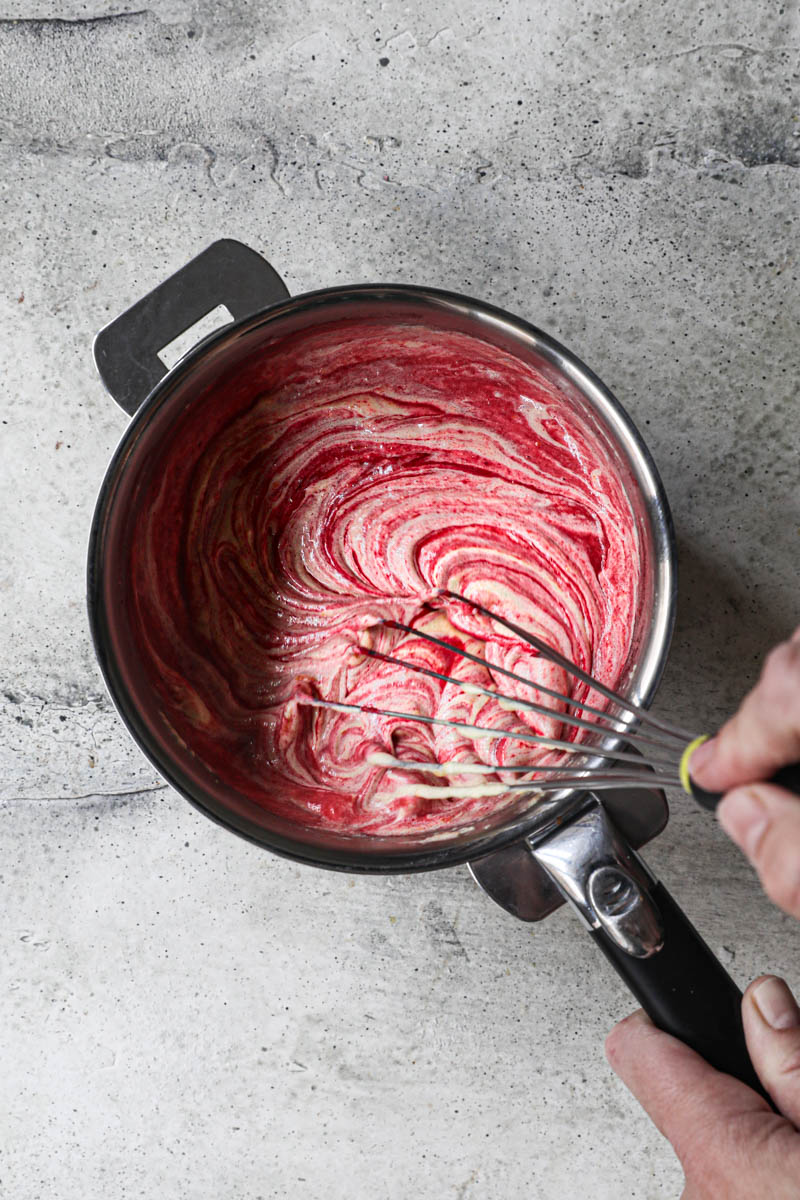 One hand whisking the sugar/yolks with the cranberry puree.