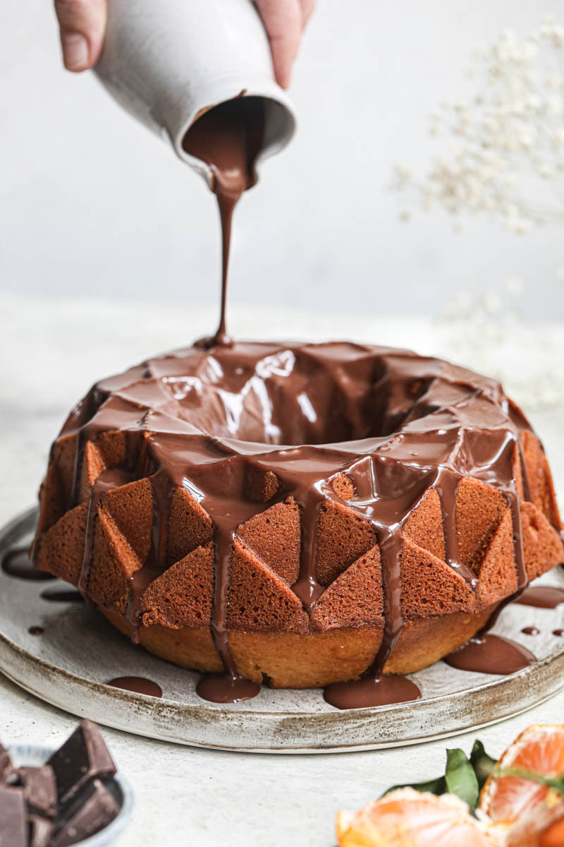 Chocolate ganache being poured over a cake.