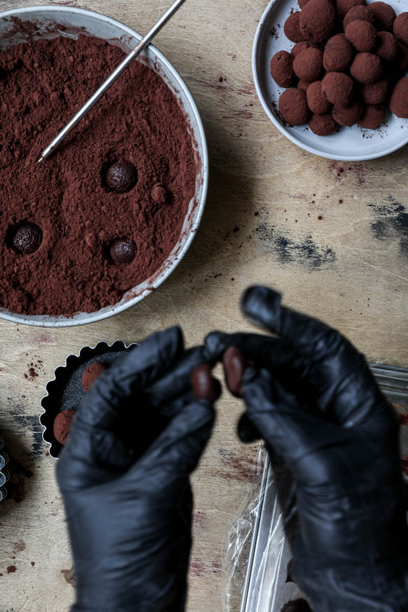 2 hands putting together ganache half balls to form a truffle