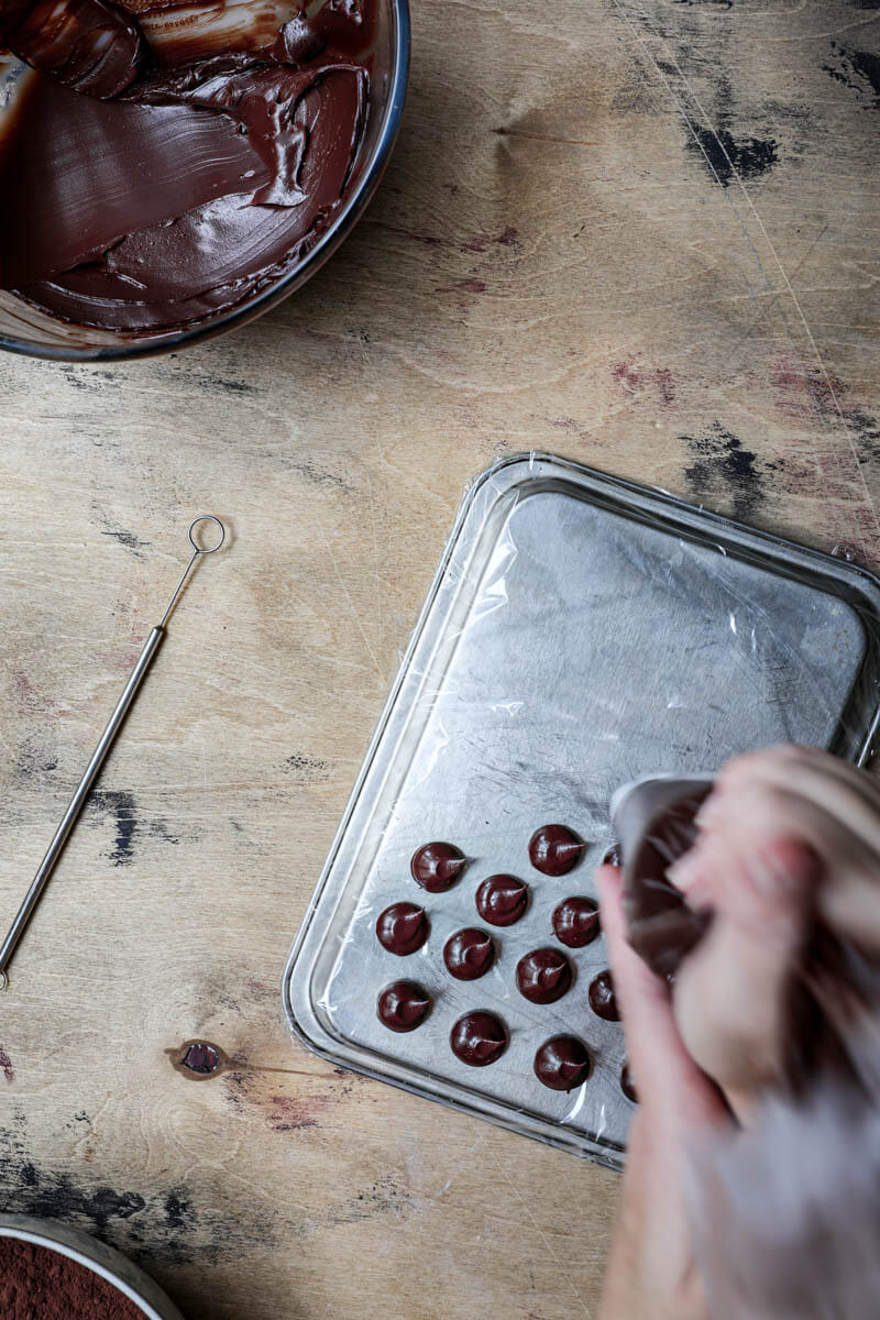 Hand piping chocolate ganache balls on a baking tray