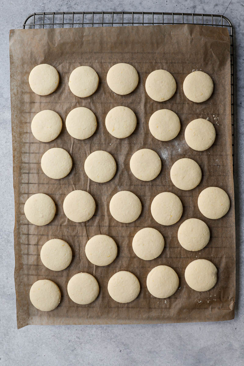 The baked alfajores cookies on top of a wire rack.