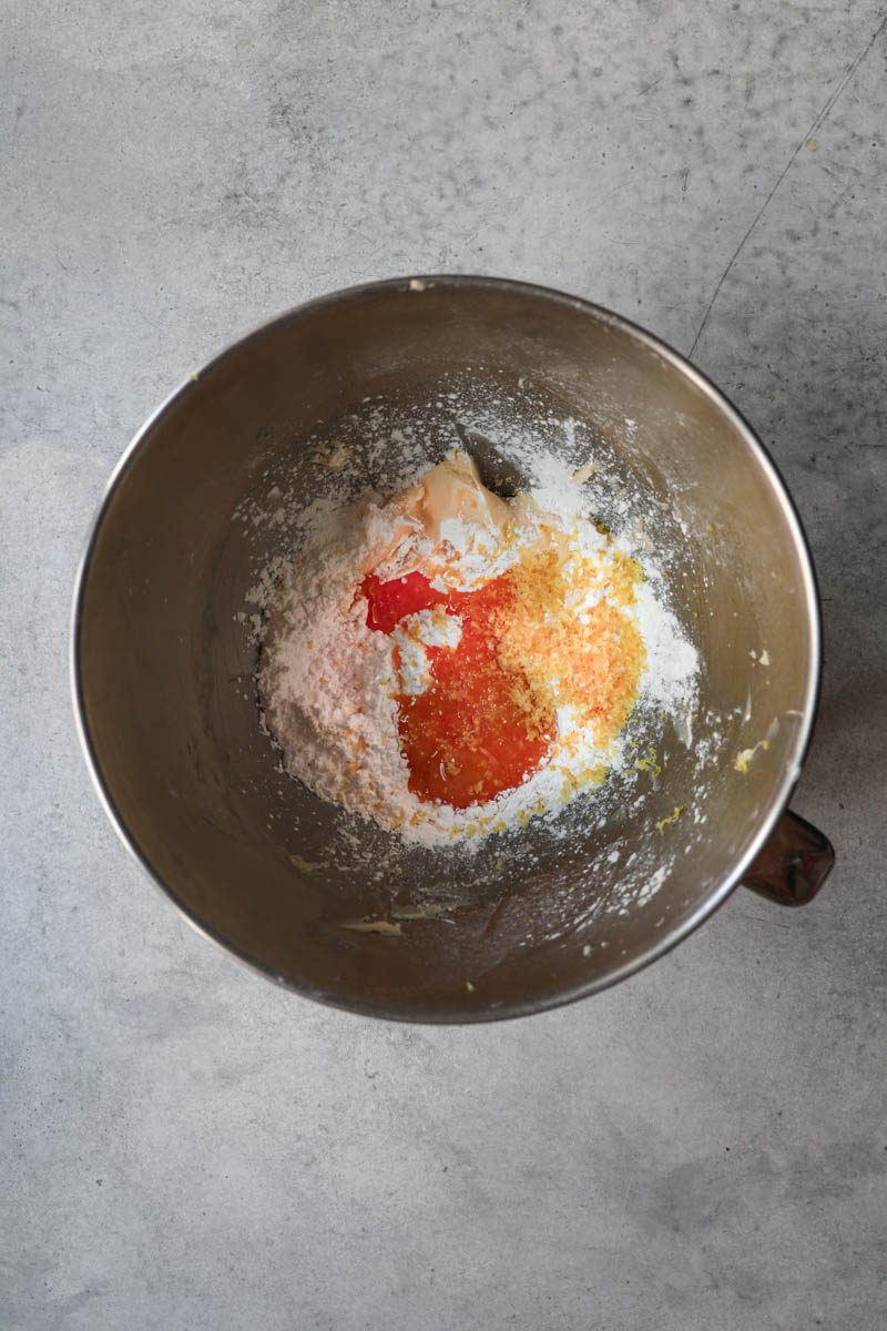 Butter, powdered sugar plus the egg yolks, lemon zest and half of the dry ingredients inside a mixing bowl to make this alfajores recipe dough.