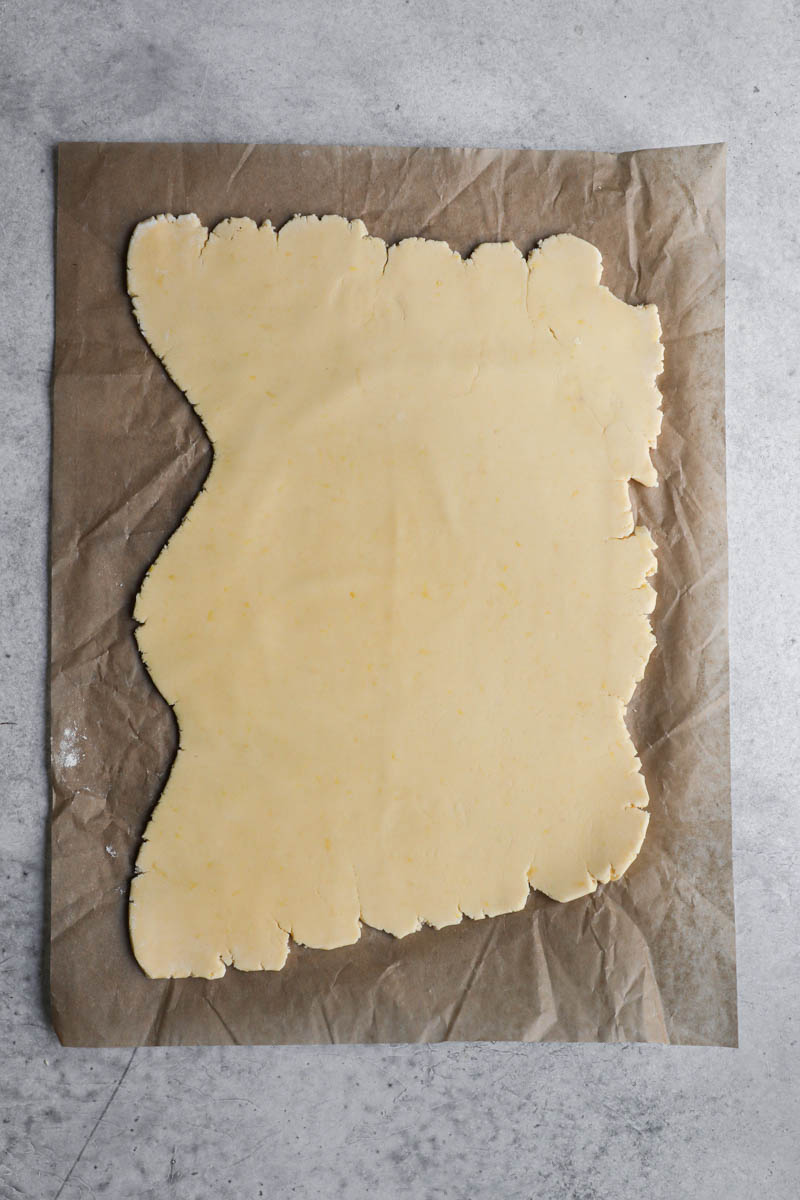 The rolled out cornstarch cookie dough on top of a parchment paper.