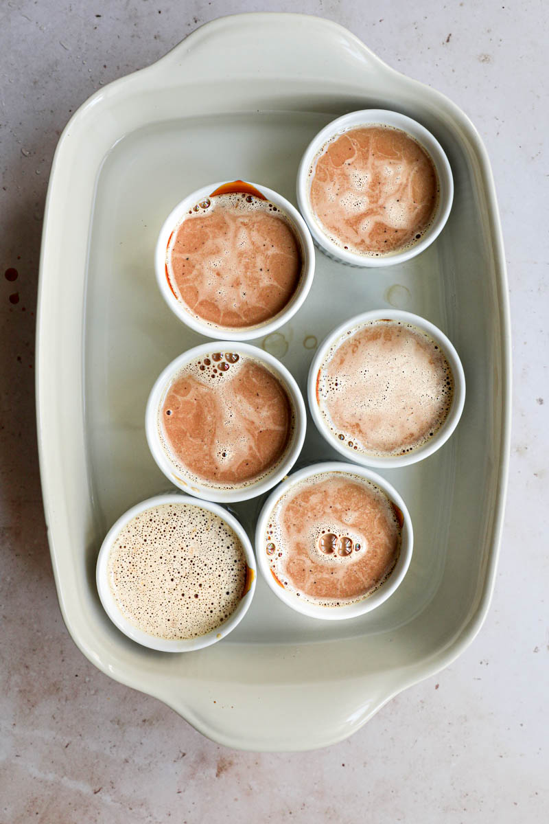 Baking the mini-individual dulce de leche flan: the ramekins placed in a baking tray filled with the dulce de leche flan batter.