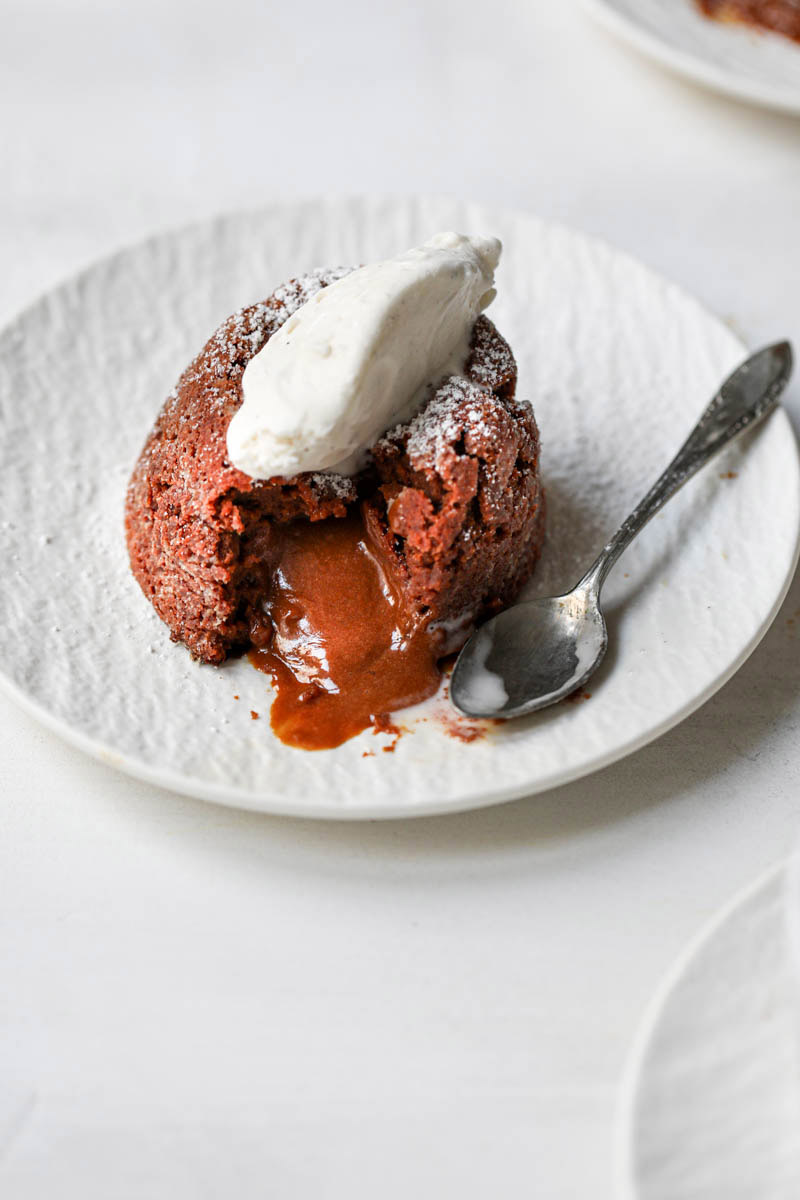 Closeup of the dulce de leche lava cake with a scoop of ice cream and a spoon on the side as seen from the side.