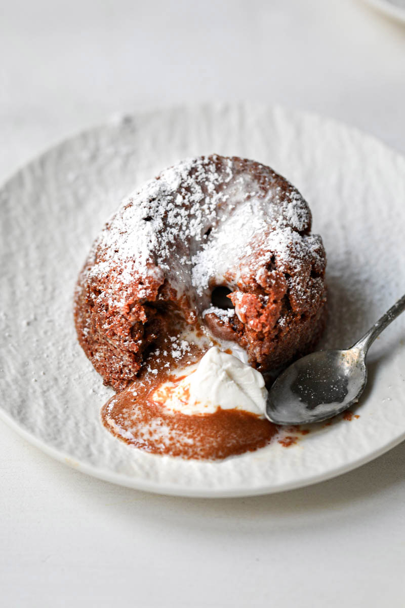 Closeup of the dulce de leche lava cake with a scoop of melted ice cream and a spoon on the side.