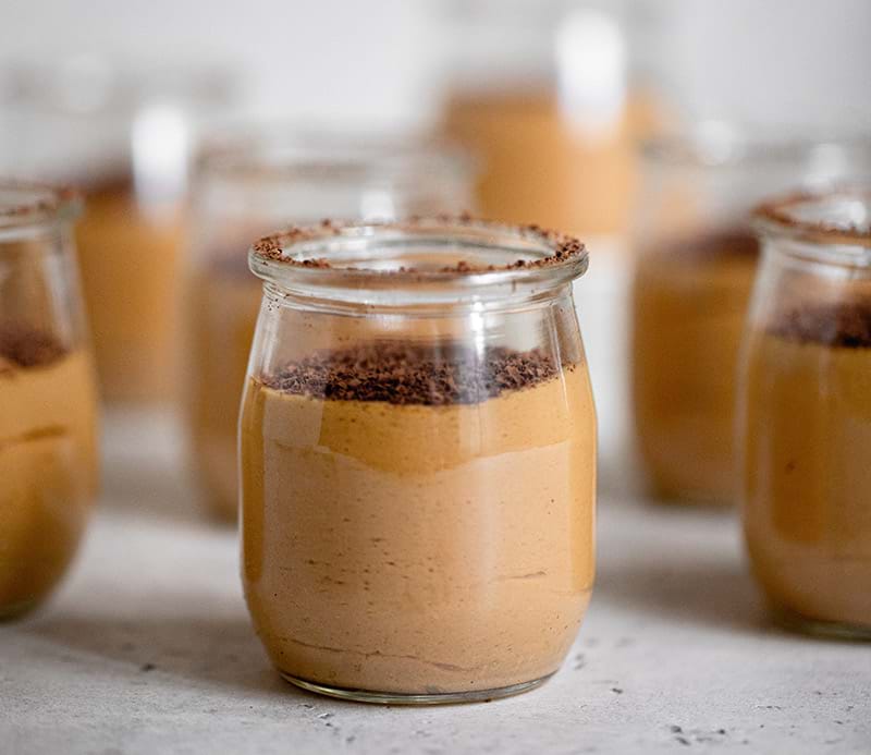 90° shot of one dulce de leche mousse with the rest blurred in the back