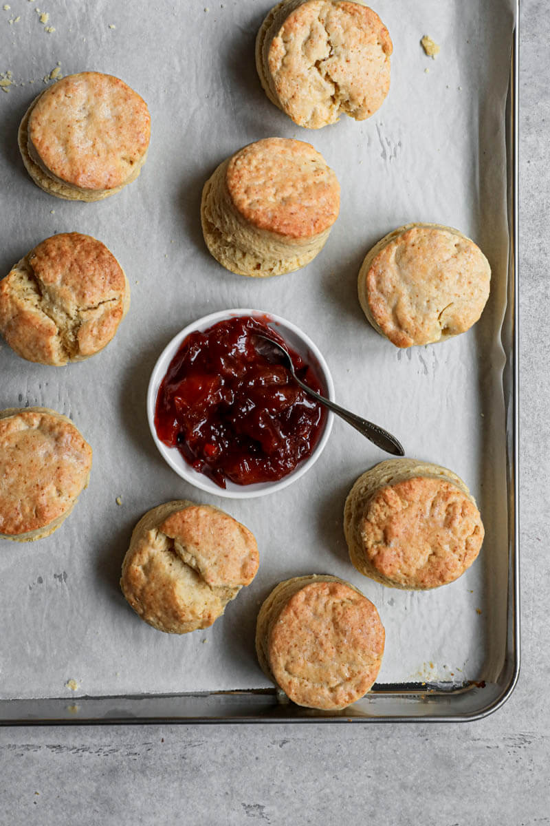 Baked scones on a baking tray with a mini bowl with marmalade