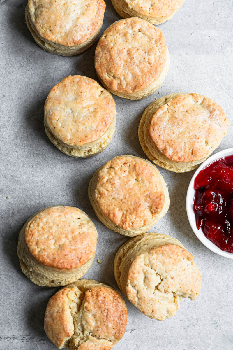 Baked scones disposed in an s shape with a bowl of marmalade on the side