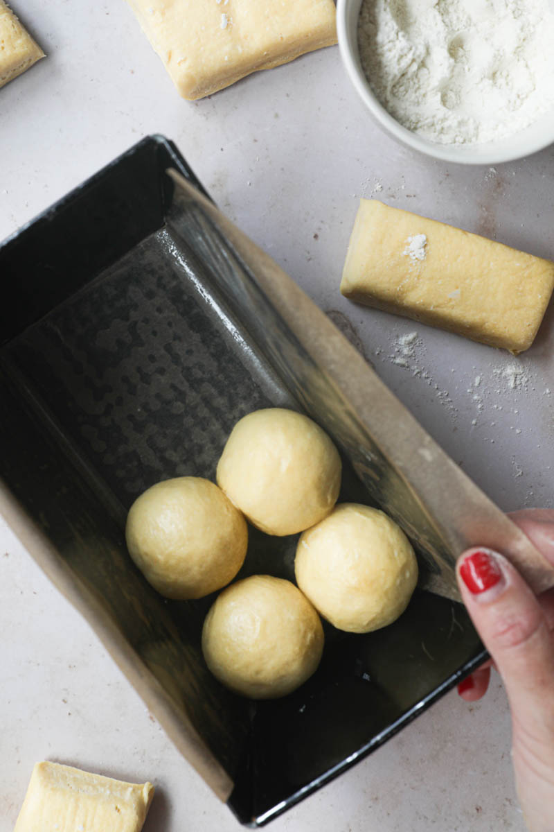 4 tight balls inside a loaf cake pan held by one hand.