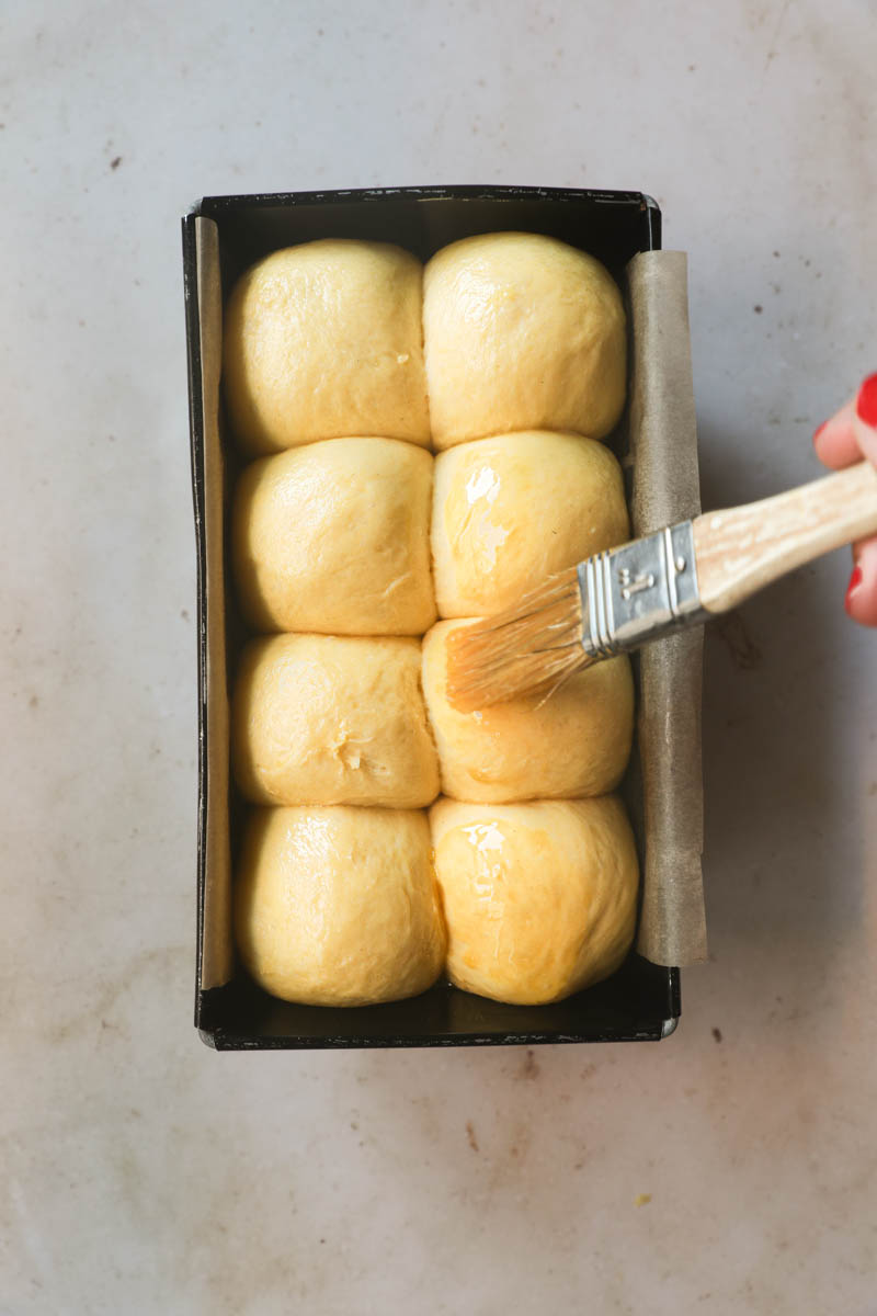 On hand paint brushing the brioche loaf bread with egg wash.