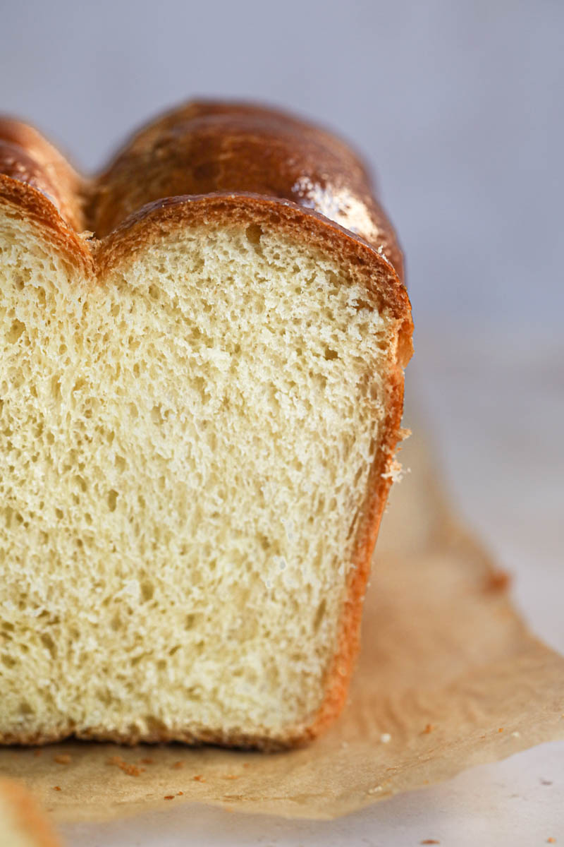 Closeup shot of half the sliced French brioche loaf bread on a piece of parchment paper.