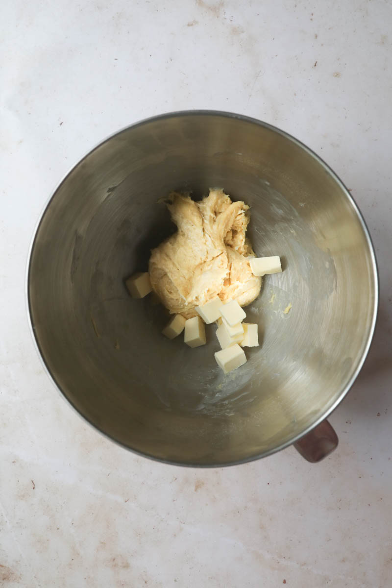 The brioche bread dough with the second half the butter inside a mixing bowl.