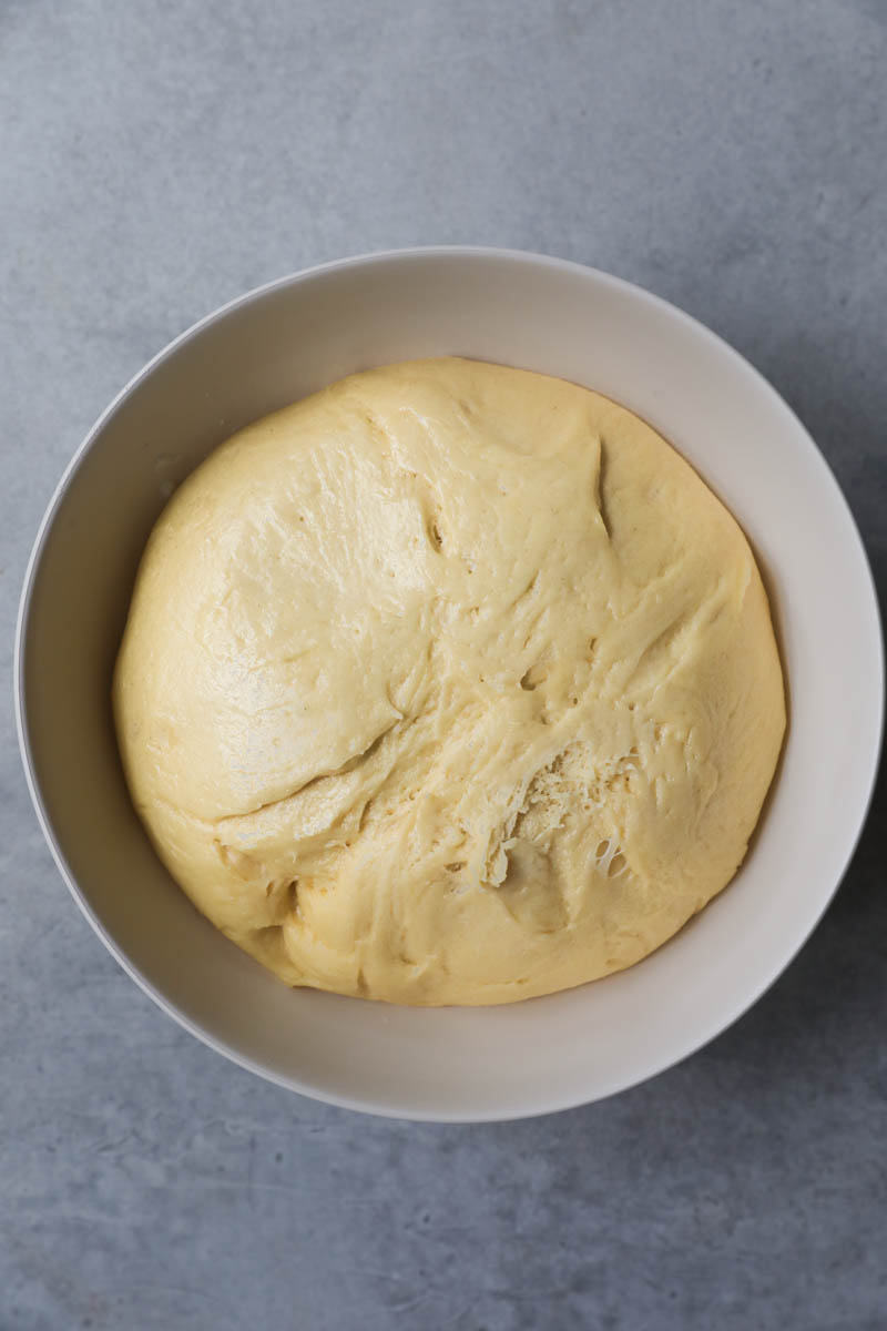 The French brioche bread dough inside a beige bowl after the first rise.