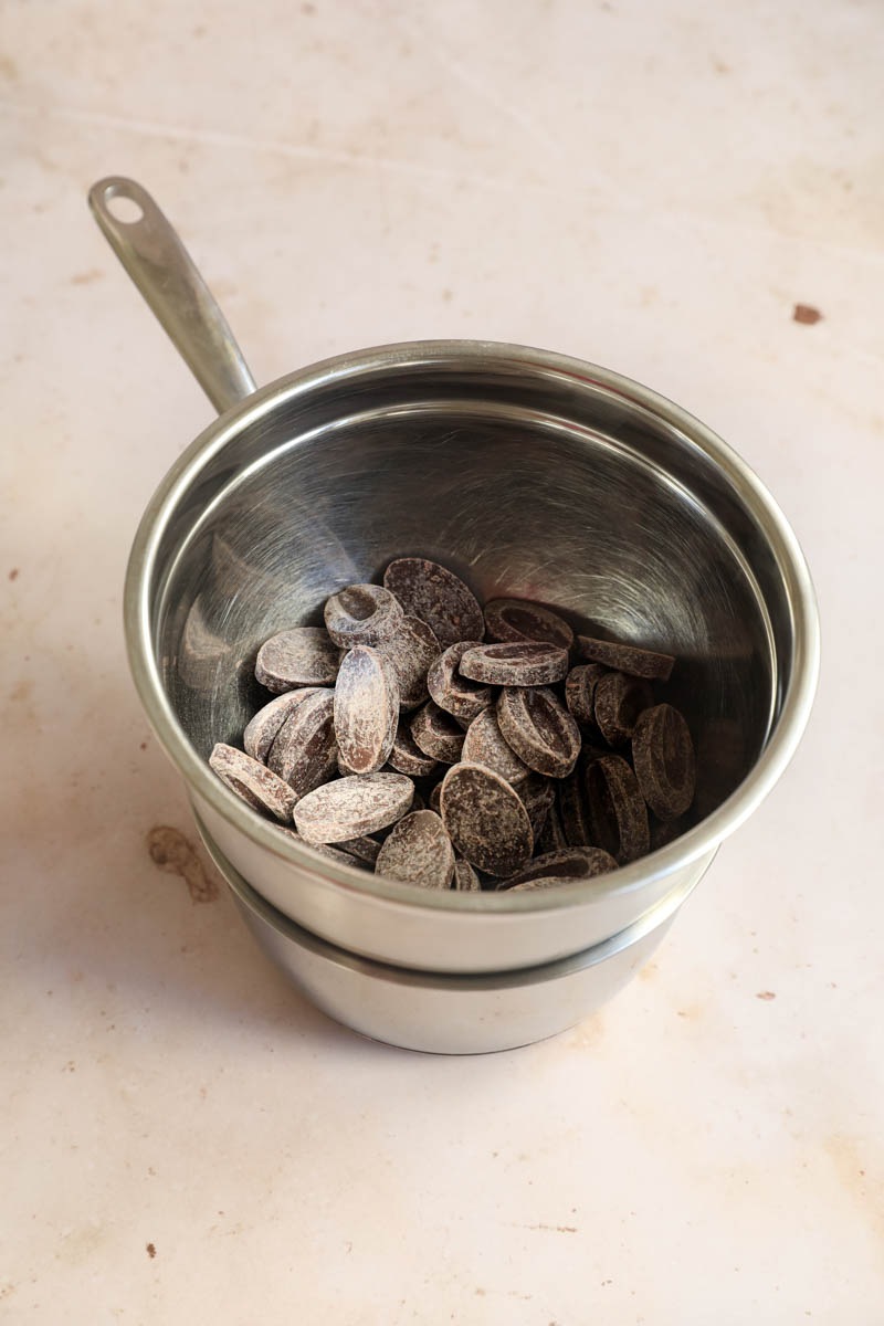 The chocolate inside a bowl placed on top of a small pan.