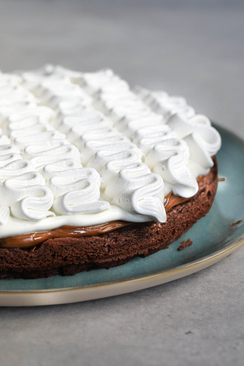 The French chocolate cake filled with whipped cream and meringue on a blue plate.