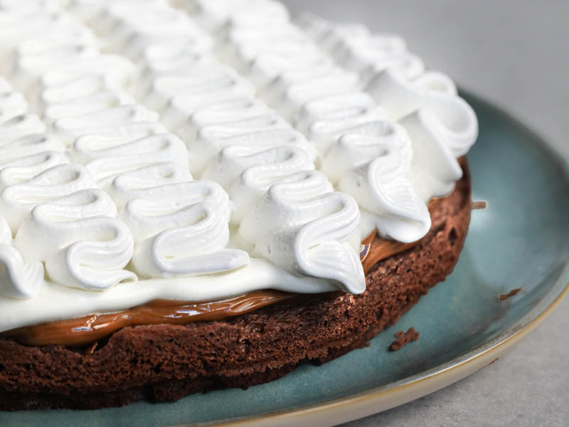 The French chocolate cake filled with whipped cream and meringue on a blue plate.