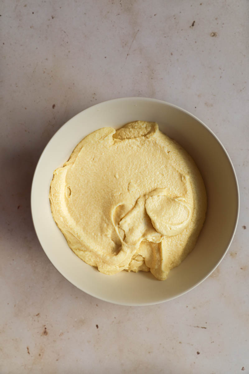 The eggs/sugar/butter mixture inside a beige bowl.