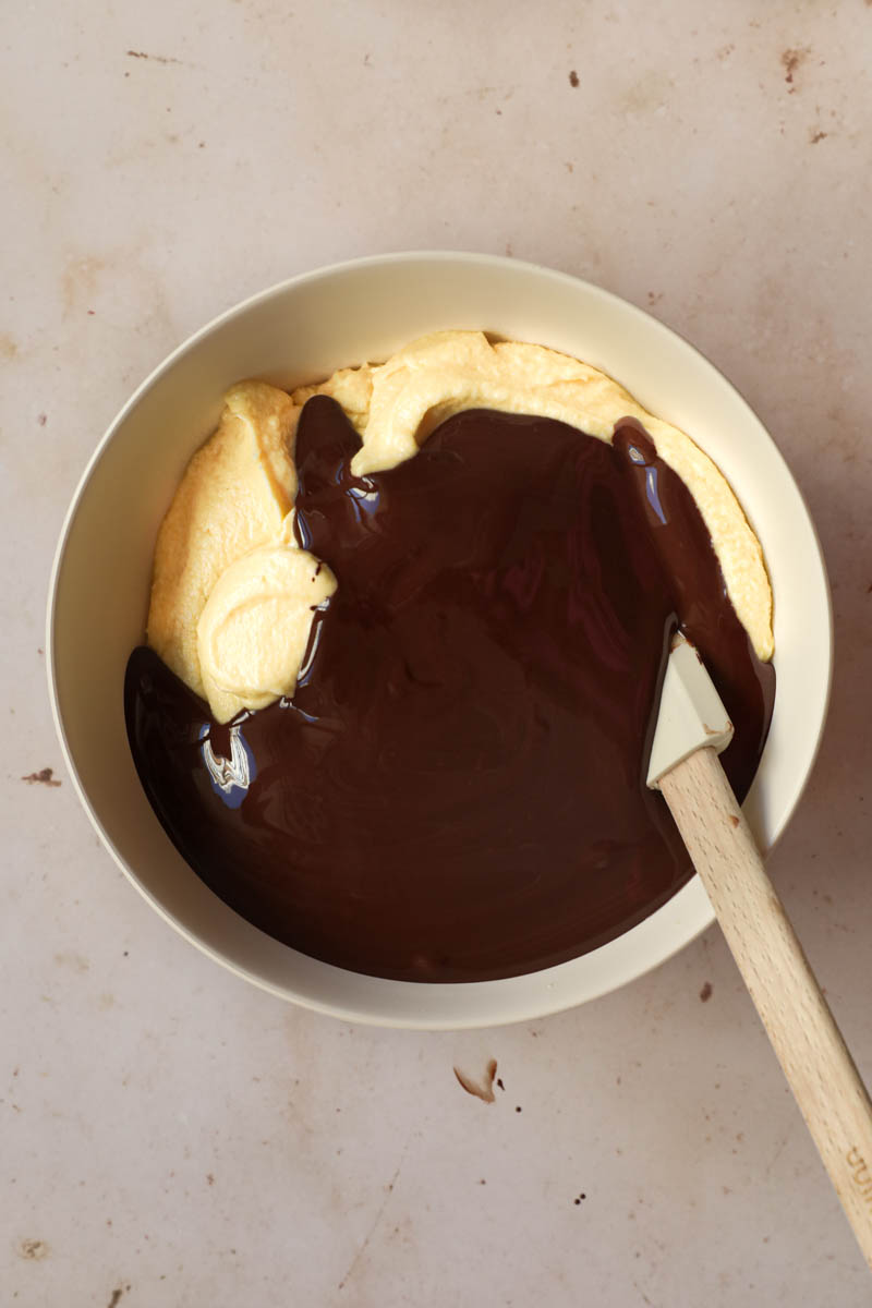 The French chocolate cake batter with the melted chocolate on top inside a beige bowl.