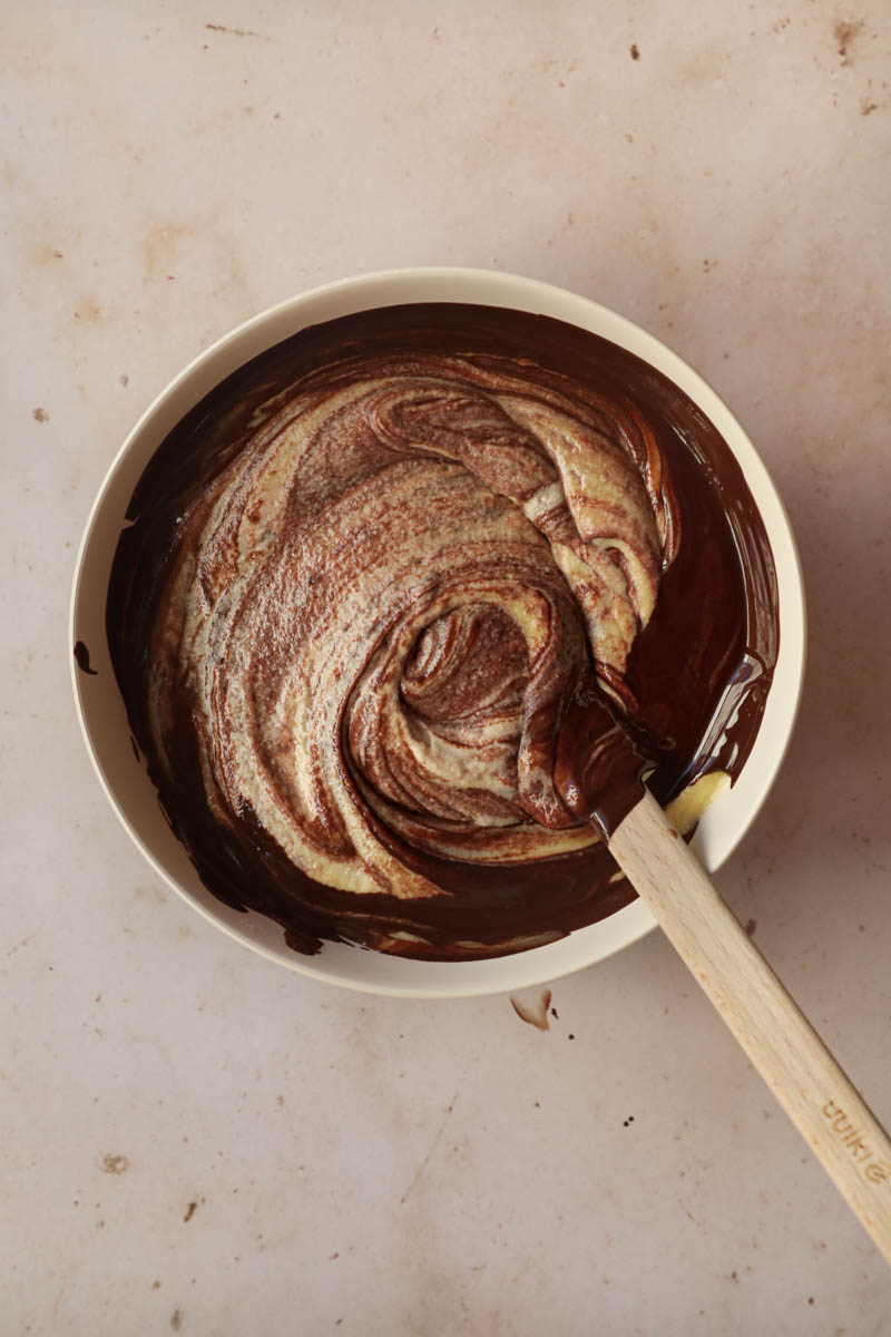 The French chocolate cake batter being mixed inside a beige bowl.