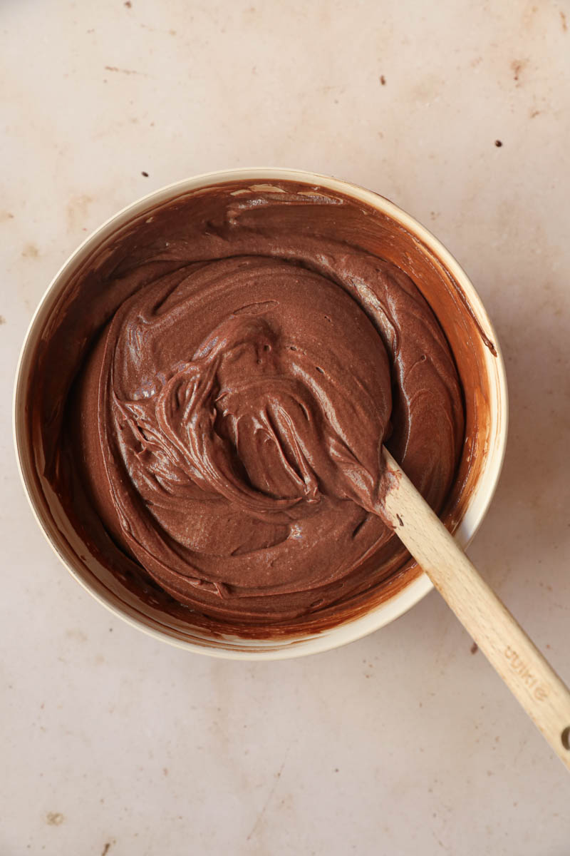 The French chocolate cake batter inside a beige bowl with a spatula inside the bowl.