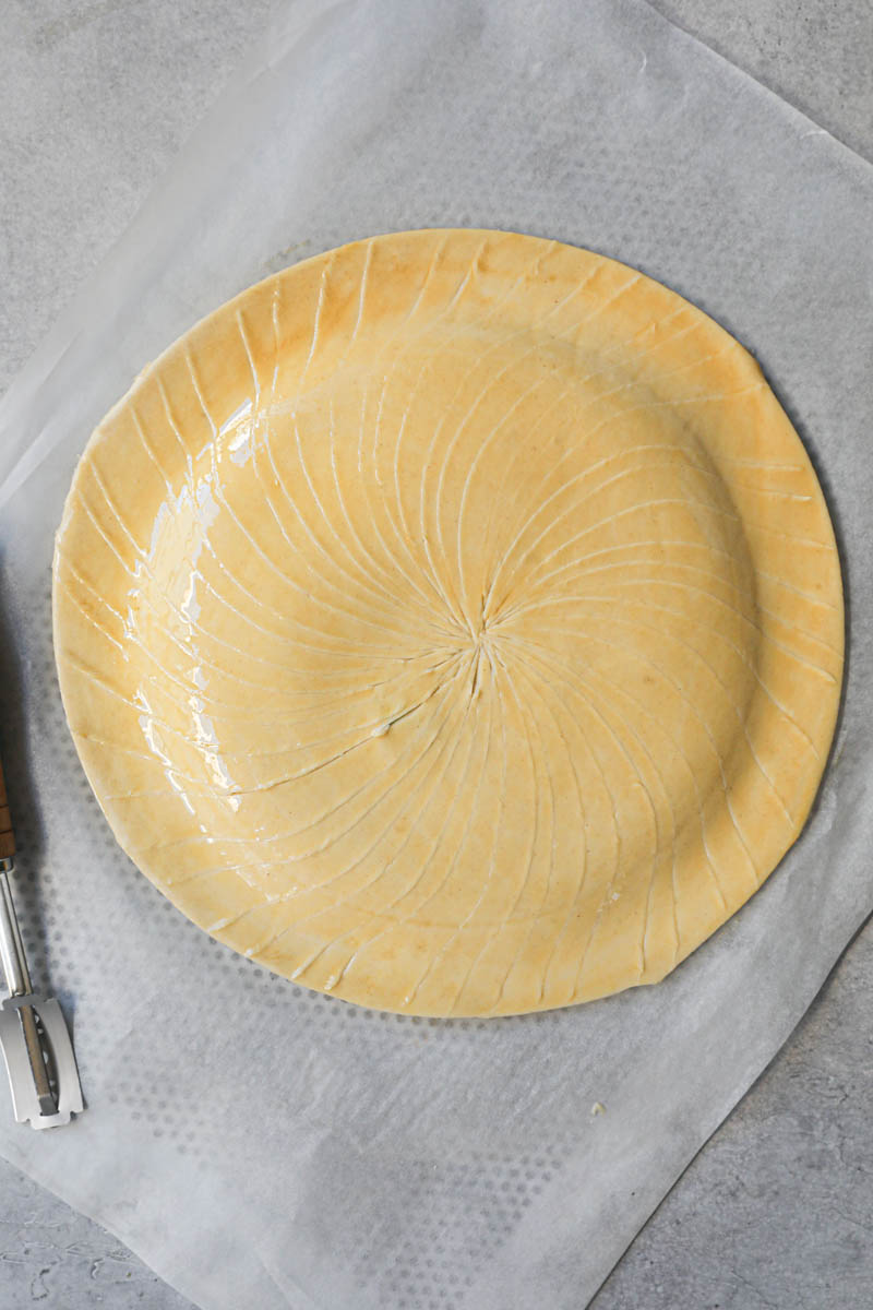 The scored French King cake over a baking tray lined with parchment paper.