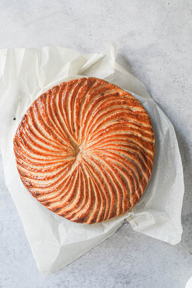 The baked French King cake over a wire rack, brushed with simple syrup.