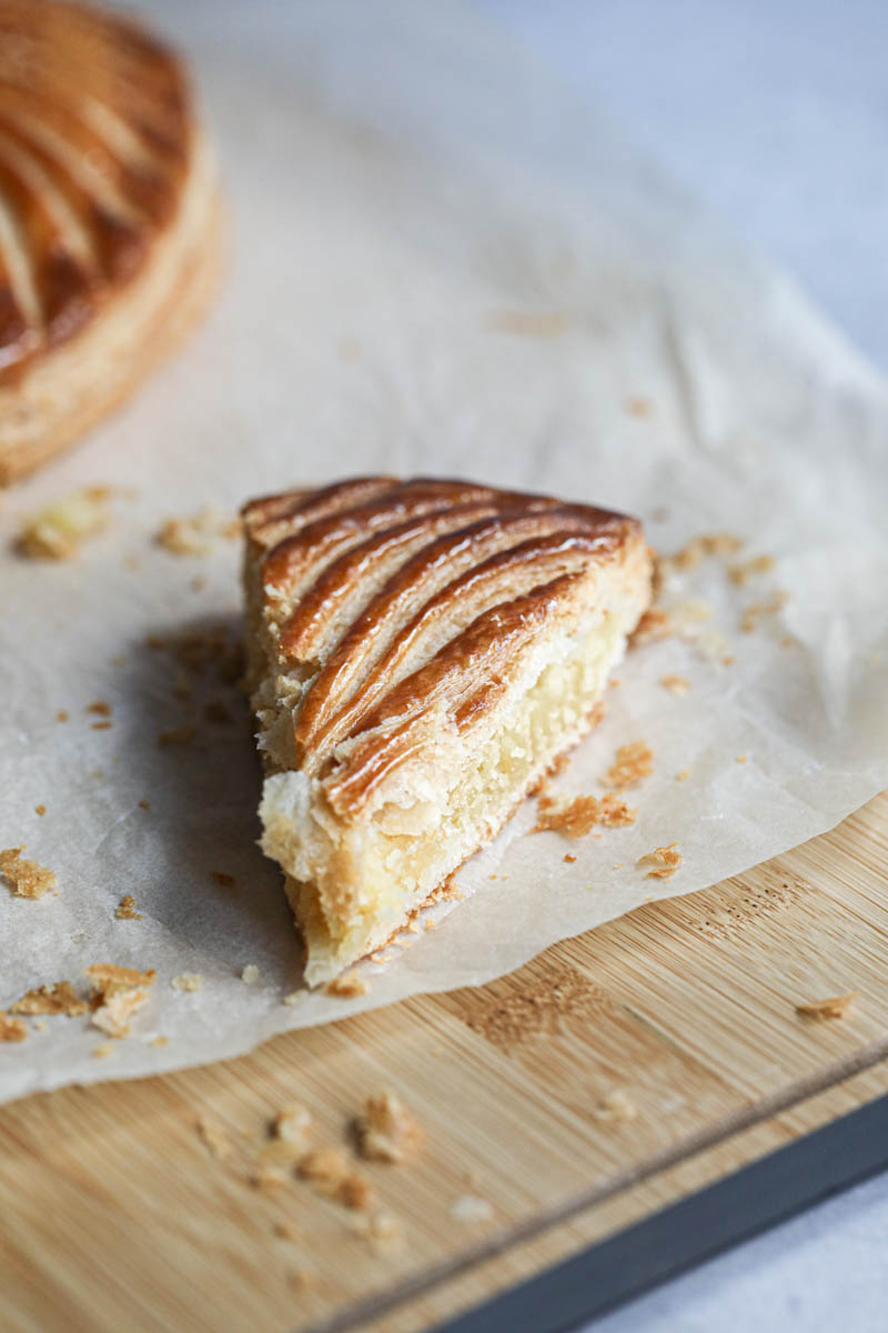 A slice of French King cake on a wooden board.