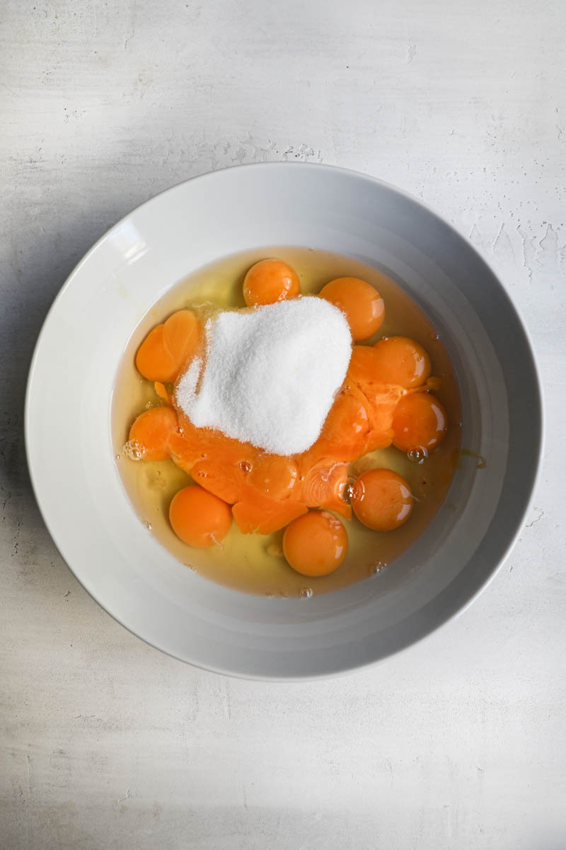 A bowl with the eggs, the egg yolks and half the sugar, some of the flan ingredients.
