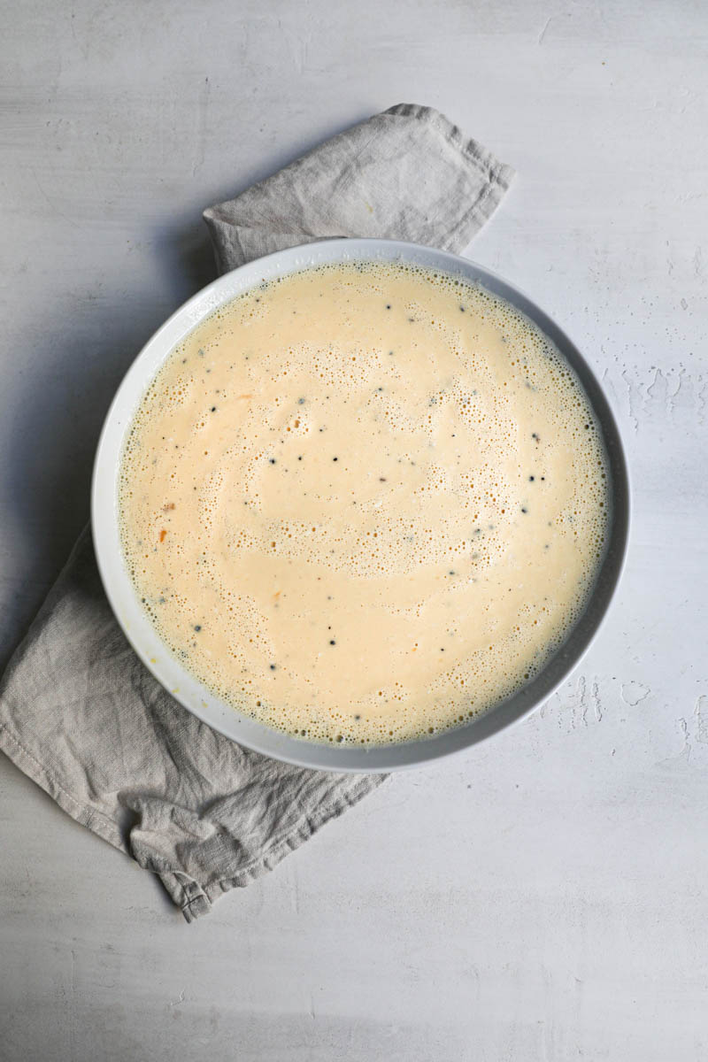 The flan batter mixed and ready inside a white bowl over a white linen.