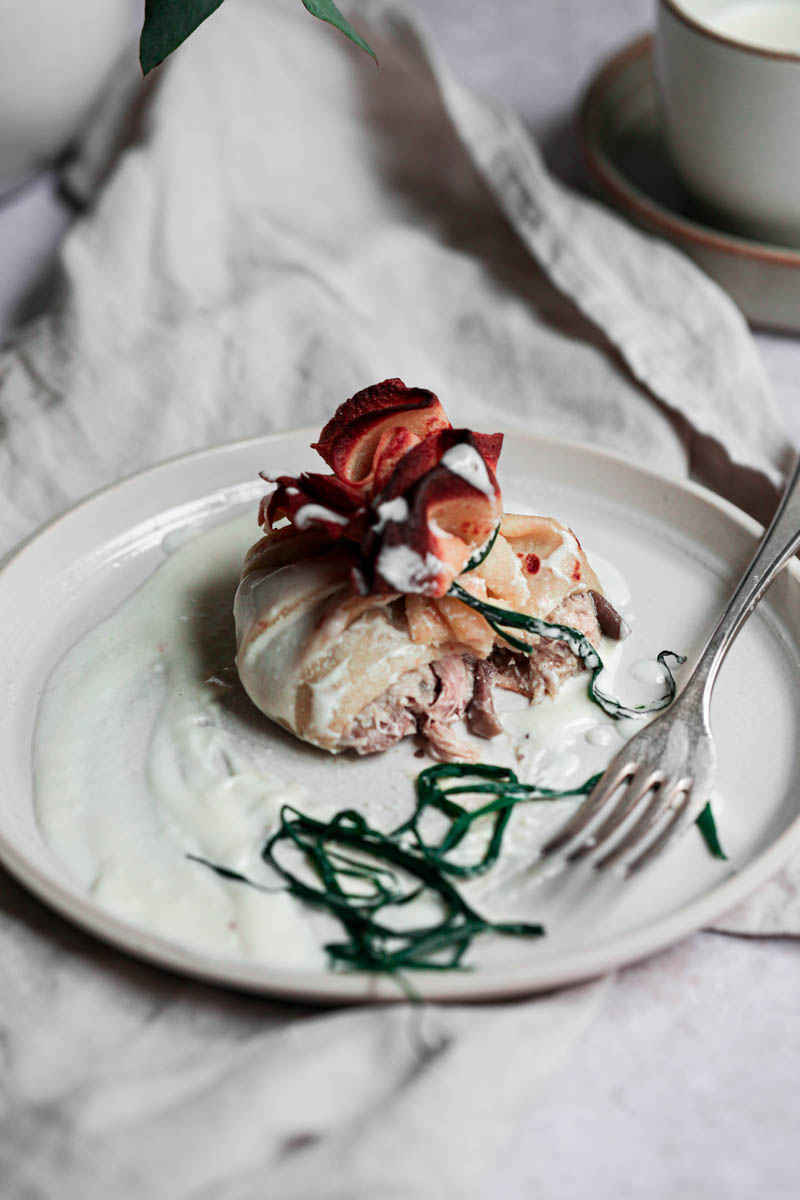 One chicken crepe on a beige plate with a fork on the side.