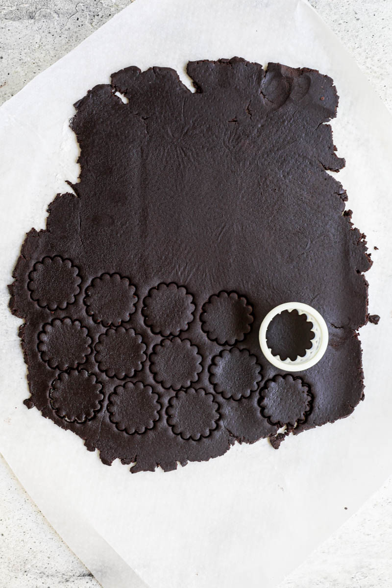 Shape and bake the homemade Oreo cookie: The rolled-out and cut out Oreo cookie dough on a piece of parchment paper.