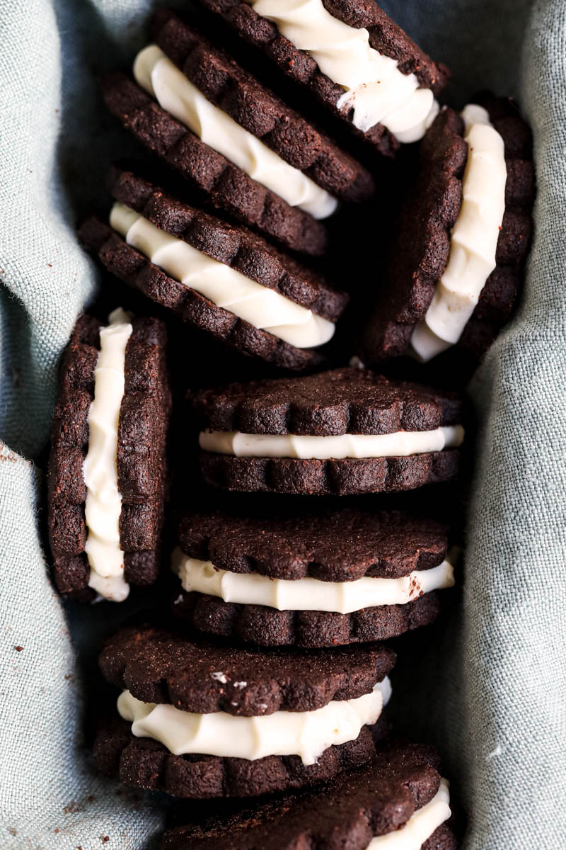 The filled homemade Oreo cookies seen from above inside a cake pan covered with a blue linen.