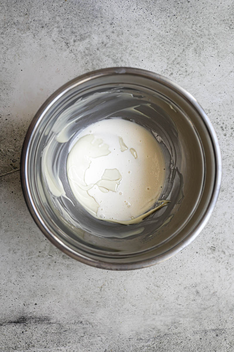 Making the white chocolate ganache cream filling: Melted white chocolate and hot heavy cream in an inox bowl.