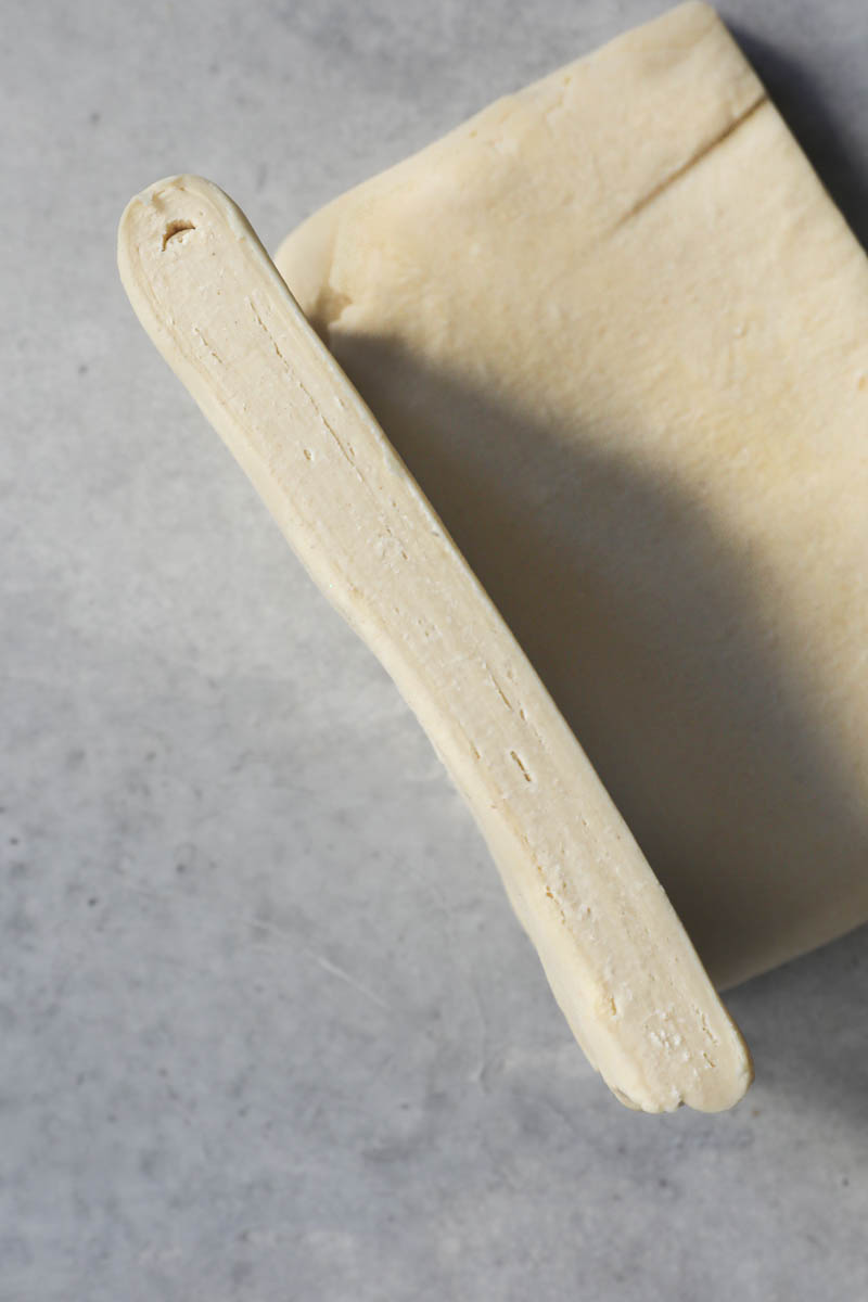 The finished rough puff pastry cut in half, one half on the work surface the second half next to it standing up so the layers can be seen.