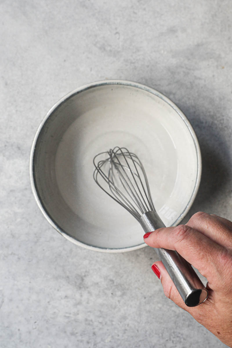 One hand whisking the salt and the water for the rough puff pastry dough.