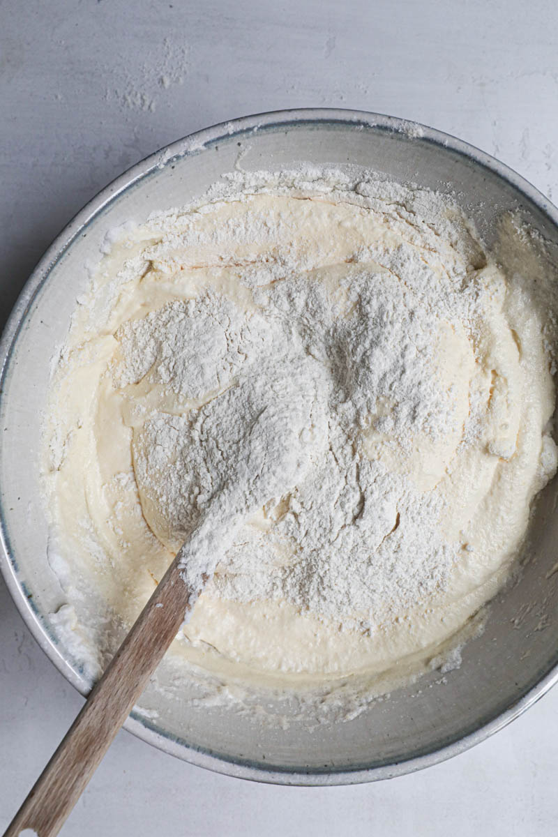 The ladyfingers cookies batter plus the flour on top with a spatula inisde the bowl.