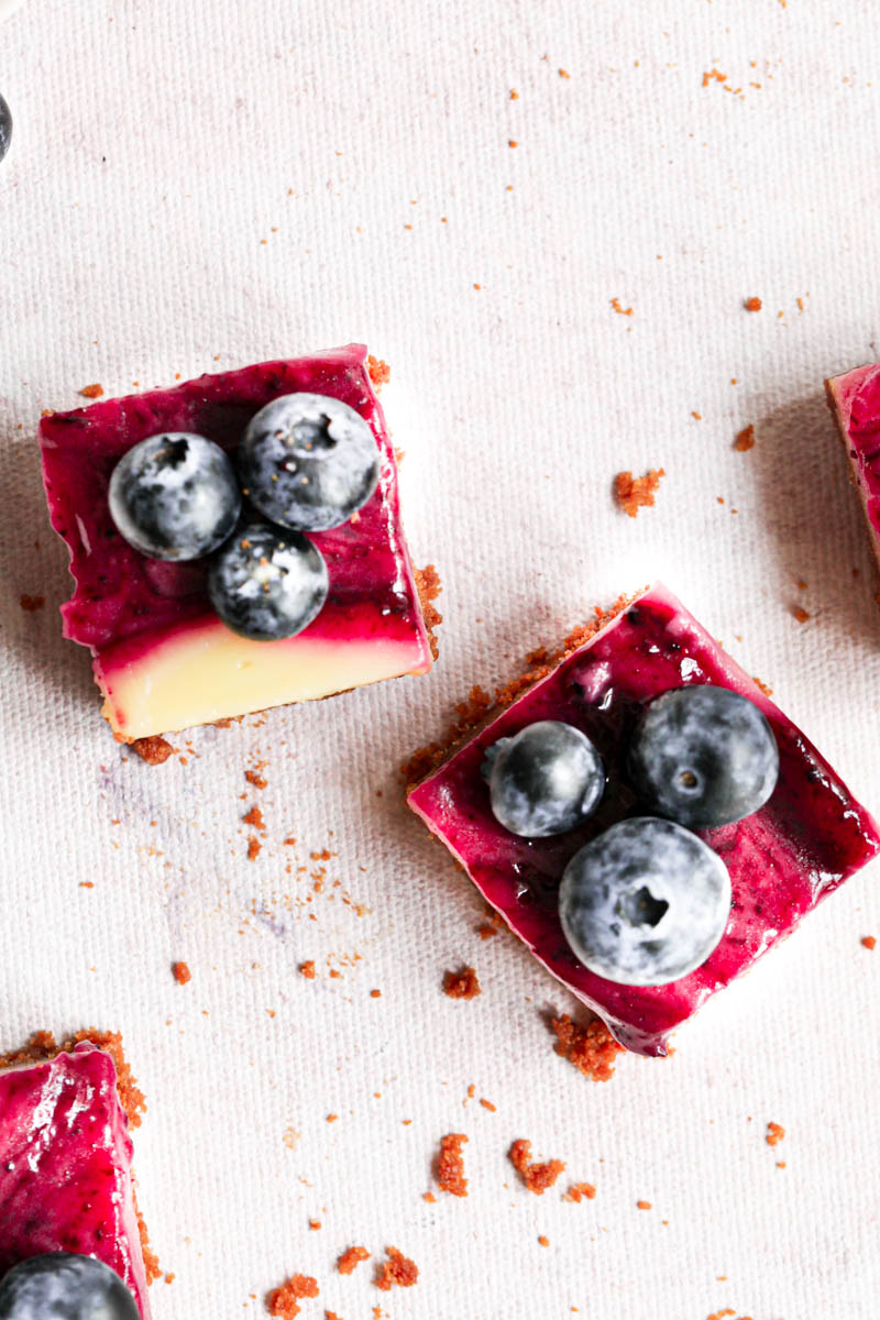 Overhead shot of 3 creamy lemon bars sliced into squares over a pink backdrop.