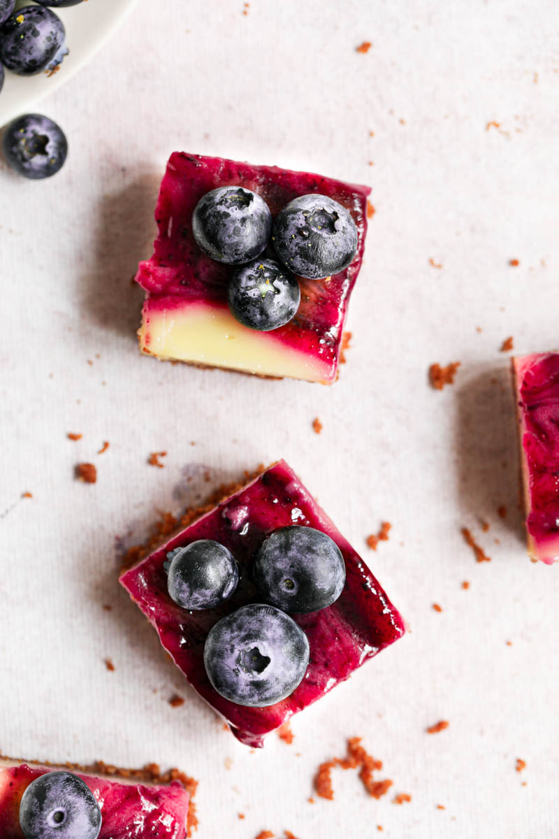 Overhead shot of 3 creamy lemon bars sliced into squares over a pink backdrop.