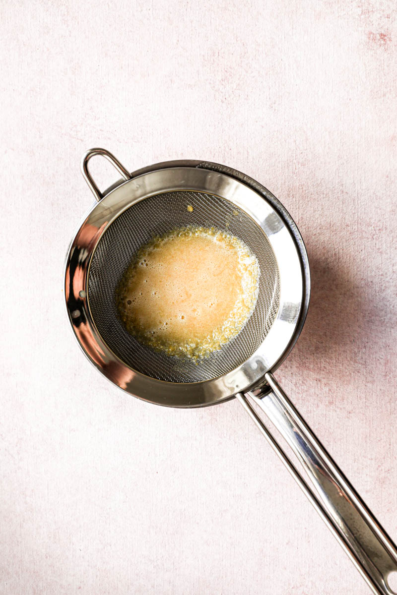 Making the lemon cream for the square lemon bars: straining the lemon cream into the small pan before bringing it to a boil.