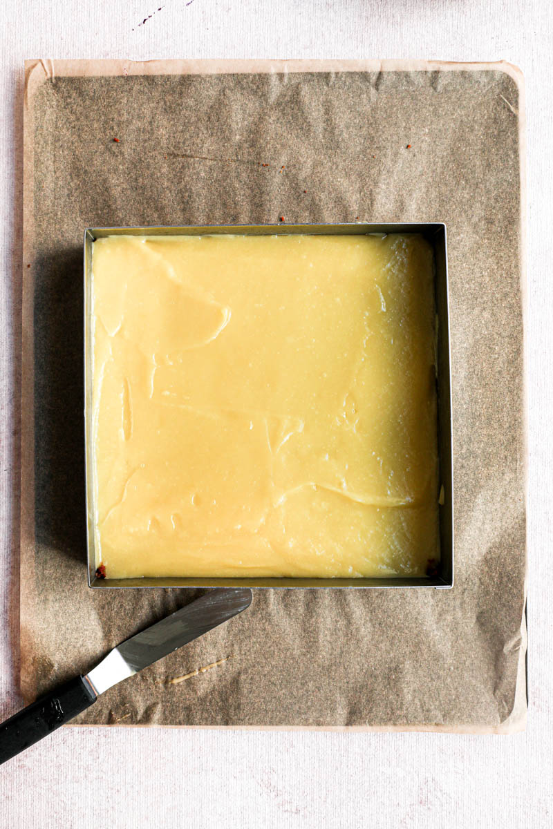 The cake ring placed on a baking tray lined with parchment paper filled with the lemon cream.