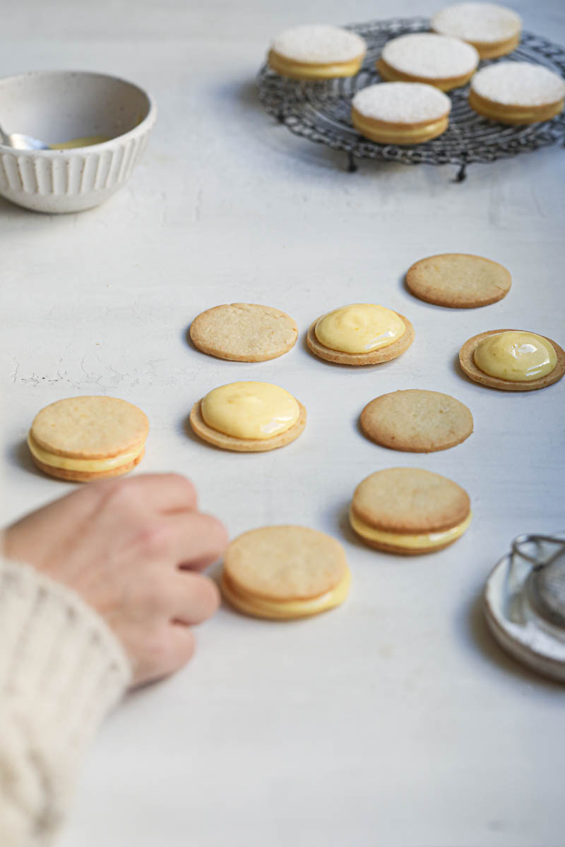 One hand closing the lemon curd cookies.