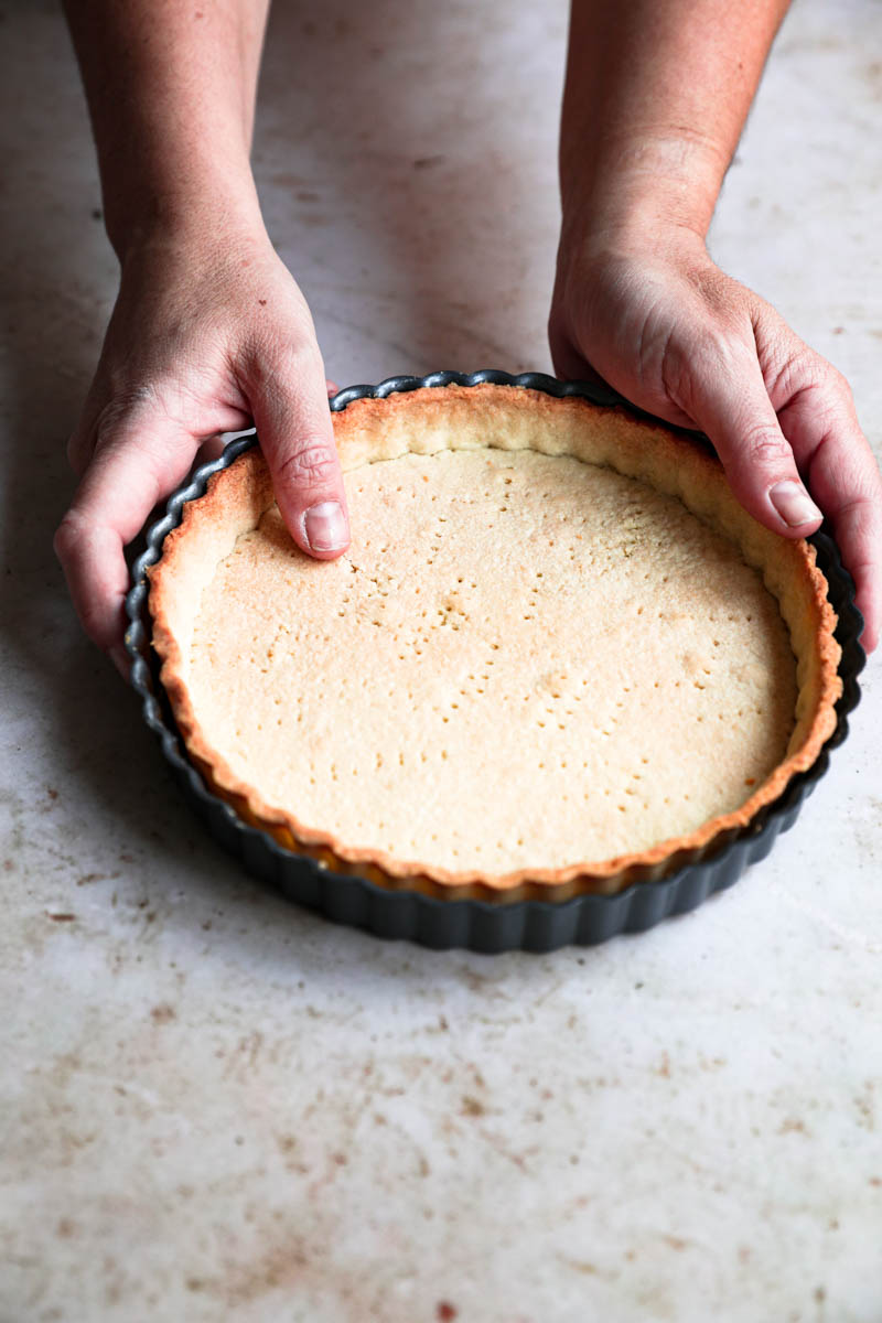 Two hands holding the baked shortbread crust.