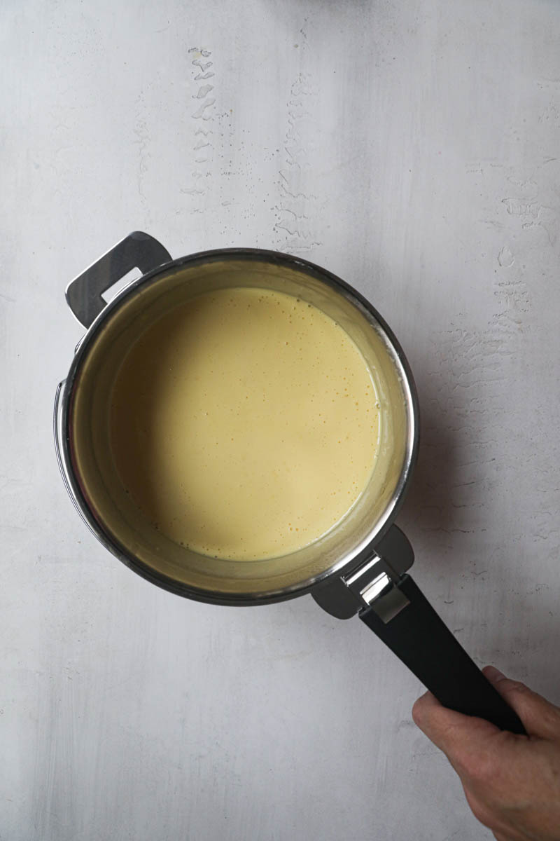 The lemon curd ready inside a pan with a black handle.