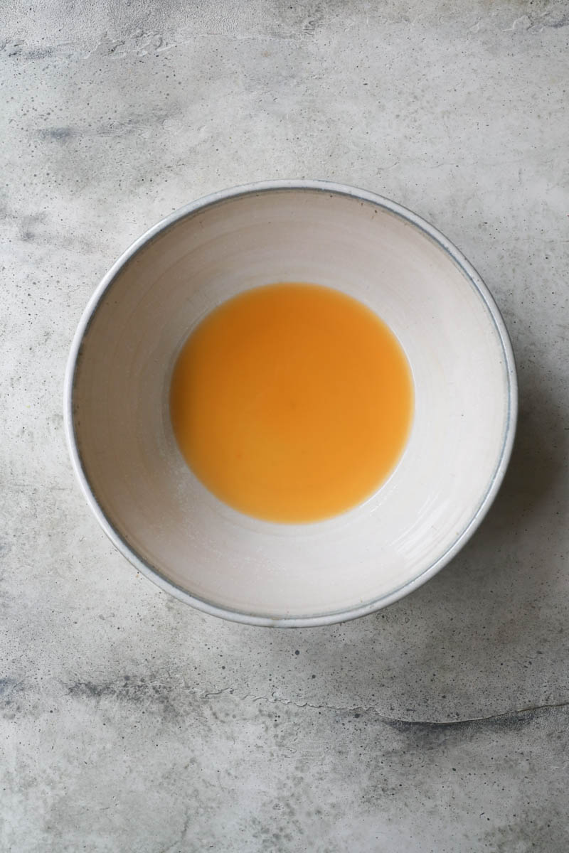 A grey bowl with the orange and mandarin juice.